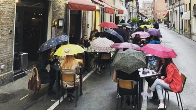 Clienti rimangono seduti a cena fuori dal ristorante nonostante la pioggia