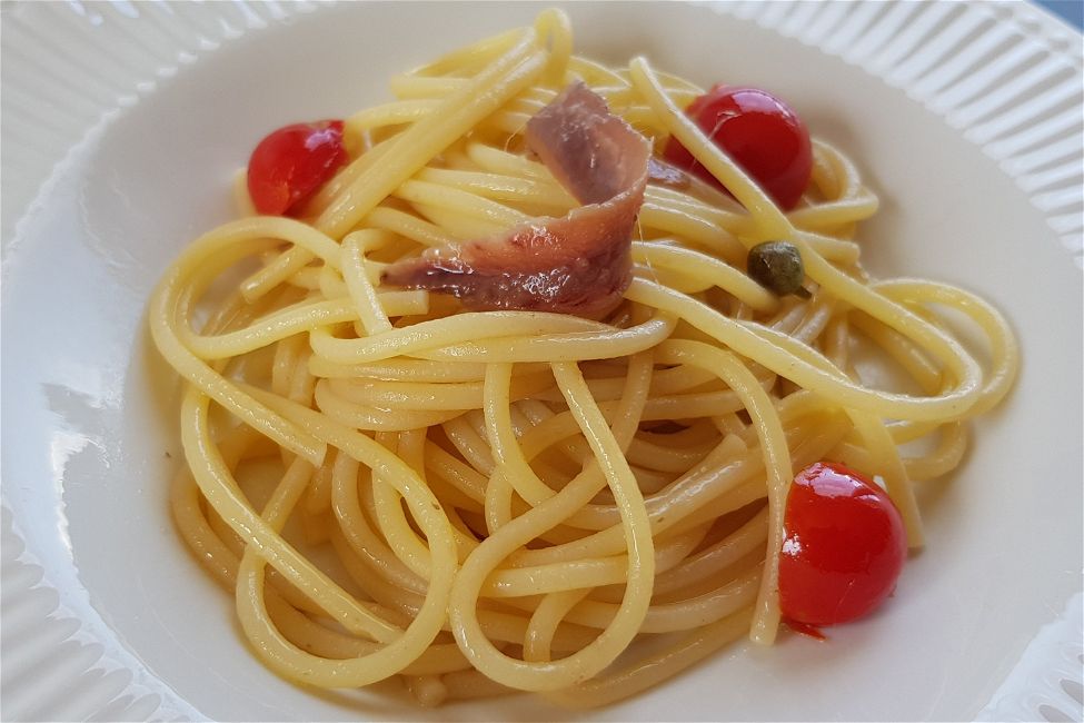Spaghetti con alici, pomodorini e capperi