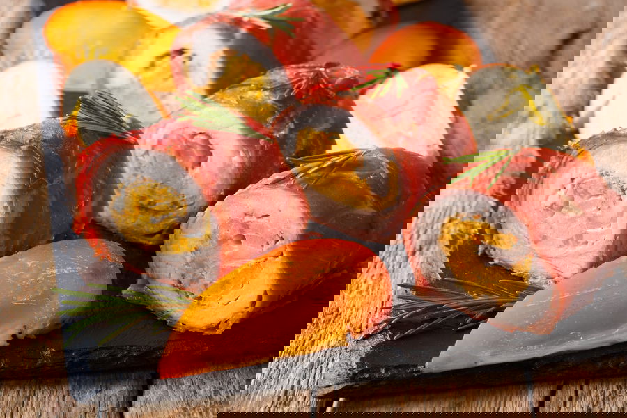 Rotolini di maiale avvolti nel prosciutto, farciti con cachi e caprino