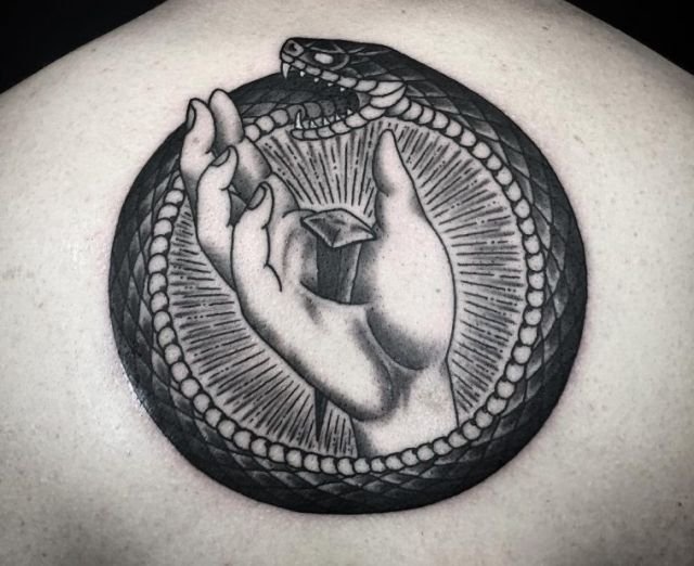 Un esempio molto suggestivo di tatuaggio di oroboro sulla schiena. L'oroboro è uno dei simboli dell'esoterismo più conosciuti