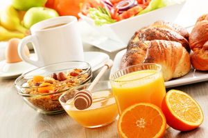 Breakfast including coffee, bread, honey, orange juice, muesli a