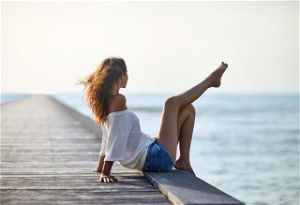 Sexy beautiful woman relaxing on pier with sea view