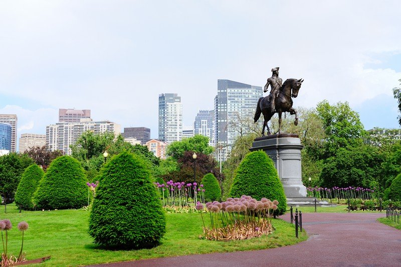 George Washington statue as the famous landmark in Boston Common Park with city skyline and skyscrapers.